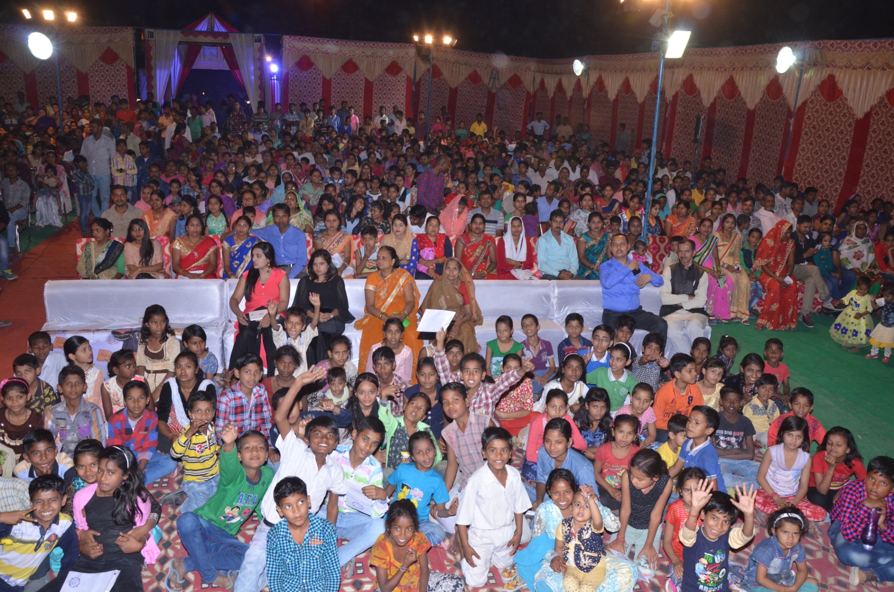 A community gathering at a Luv 2 Care event — hundreds of families, children in the front, elders and volunteers behind.